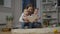 Wide shot portrait of young Caucasian mother reading book for twin daughters sitting in living room. Happy charming