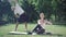 Wide shot of positive sportswoman sitting on yoga pose as strong sportsman stretching at the background. Happy Caucasian