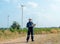 Wide shot of professional technician worker hold laptop and look to left side in front of windmill or wind turbine with blue skay