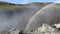 Wide shot of a rainbow spanning from a misty valley in a mountainous area