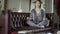 Wide shot of relaxed Asian young slim woman sitting in lotus yoga position on couch in living room meditating. Portrait