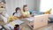 Wide shot of relaxed Caucasian children with feet on table looking at laptop and talking. Positive carefree schoolboy