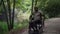 Wide shot sad young soldier in wheelchair riding in summer forest looking away. Front view portrait of African American