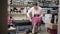 Wide shot of serious Caucasian senior woman sitting in shoe store and trying on high-heels. Portrait of elegant female