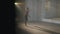 Wide shot of slim adult ballerina training in backlit fog indoors. Confident hard-working Caucasian female ballet dancer