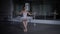 Wide shot slim agile ballerina in white dress tutu performing arabesque movements in dark studio indoors. Portrait of