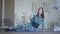 Wide shot of slim Caucasian woman in sportswear working out on exercise mat. Portrait of young brunette sportswoman