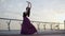 Wide shot of slim elegant ballerina bending back as birds flying away. Back side view of professional classical ballet