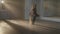 Wide shot of slim talented ballerina rehearsing dance with beige scarf in ballet studio backlit. Hard-working ballet