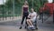 Wide shot of smiling young woman posing with man in wheelchair on sports ground. Portrait of happy loving Caucasian