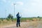 Wide shot of technician worker hold laptop and look to the monitor for working in front of windmill or wind turbine with blue skay