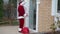 Wide shot thief in Santa Clause costume opening door on backyard on New Year's eve. Young Caucasian male burglar robbing
