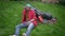 Wide shot of tired perspiring young man drying forehead with hand sitting on green backyard with lawn mower. High angle