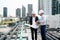 Wide shot of two engineers or technician man discuss together using building plan or drawing and they also stay on rooftop area of