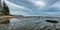 Wide shot of water in the middle of rocks near the shore under a cloudy sky in old Australia