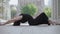 Wide shot of young ballerina lying on asphalt in city and moving slim gorgeous body. Portrait of beautiful Caucasian