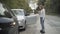 Wide shot of young Caucasian man and woman talking and gesturing looking at broken cars on roadside. Stressed male and