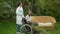 Wide shot of young doctor nurse caregiver standing with disabled patient in wheelchair outdoors. Caucasian woman taking