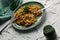 Wide spaghetti with fried vegetables topped with grated cheese and fresh dill on a modern green plate, homemade food, simple dish