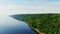 Wide tranquil river with hilly forestry bank under blue sky