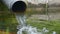 A wide tube with splashing water falling into a lake in slo-mo