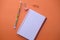 Wide view of blank spiral note pad and pen on orange color background