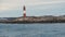 Wide view from boat of Les Eclaireurs Lighthouse on island full of cormorants