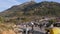 Wide view of a crowd of people and vehicles moving on the dusty road of the mountain