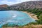 Wide view of the Hanauma Bay and tourists by the beach and in the waters snorkeling in Hawaii, USA