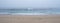 Wide view over sandy beach in autumn with dense, thick fog over the ocean.