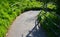 A wide walkway in the park leads directly from the slope down to the pond. has a black metal railing on the handrails. stone and c