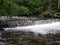 Wide waterfall on a mountain river in dark summer day Foamed water