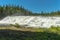 Wide waterfall with smooth water in bright summer sunshine