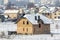 Wide winter panorama of rural land for development in quiet residential suburban area. New not finished brick house on background