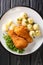 Wiener Backhendl Austrian Breaded Fried Chicken with boiled potatoes close up in the plate. Vertical top view
