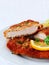 Wiener Schnitzel cut in two served with lemon slices and parsley leaves over white, vertical