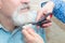 The wife cuts her husband`s beard with scissors