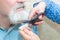 The wife cuts her husband`s beard with scissors