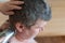Wife cuts her husband`s hair at home. Woman uses an electric hair clipper to cut man`s hair at back of his head. Middle-aged