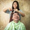 Wife cutting hair for her husband ,wood background