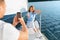 Wife Gesturing Thumbs-Up While Husband Taking Photo Relaxing On Yacht