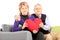 Wife and her husband sitting on a sofa and holding a red heart