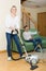 Wife hoovering room, husband relaxing
