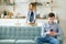 Wife takes away dishes husband sits on sofa with phone