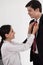 Wife tying red necktie to her husband in the office with smiling and happy