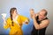 A wife in a yellow robe beats a bald husband, the concept of a family quarrel
