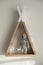 Wigwam shaped shelf with toy bear on white wall. Children`s room interior