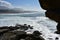 Wild beach and sea from a cliff. Big waves breaking against the rocks, foam and mist. Sunny day, blue sky, Galicia, Spain.