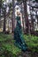 Wild beauty blonde woman long green dress in the forest