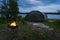 Wild camping in nature in Estonia. A tent set on the shore of a rummu quarry, a brazier with a fire. Photo at dusk